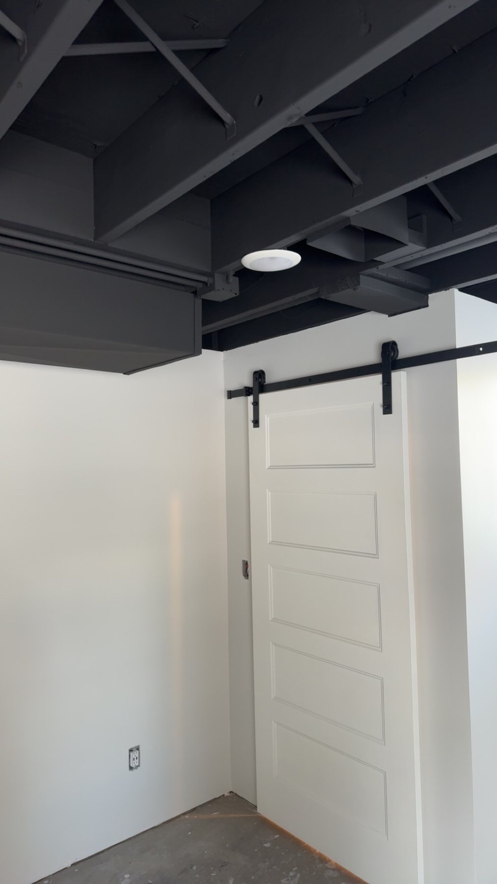 Modern open-ceiling basement painted dark gray