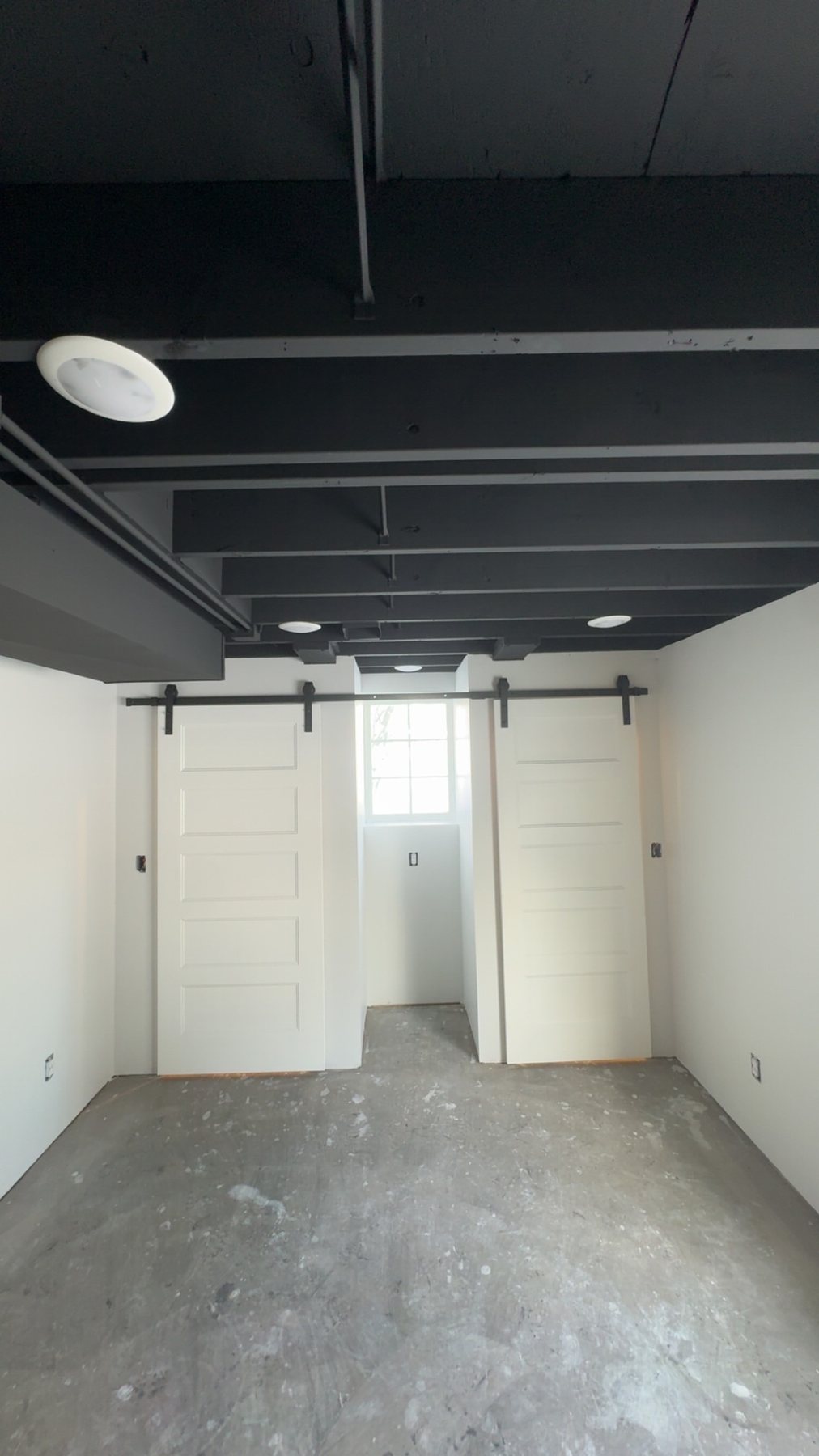 Wide view of dark open ceiling and white barn doors
